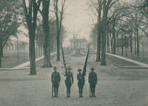 This image shows four men, all SATC cadets, presenting the national and unit colors on the Quad.