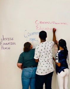 Three students write on a dry erase board