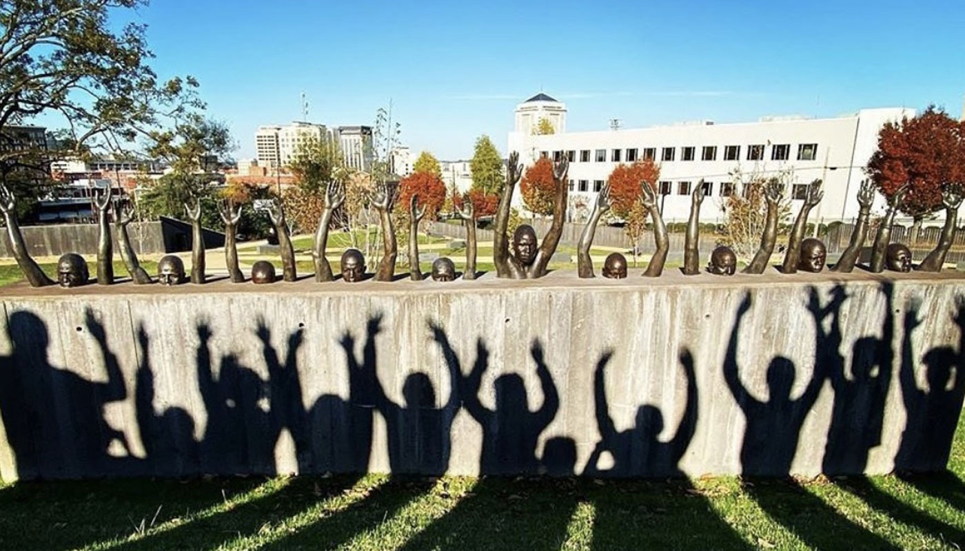 Shadows of student hands raised at EJI memorial.